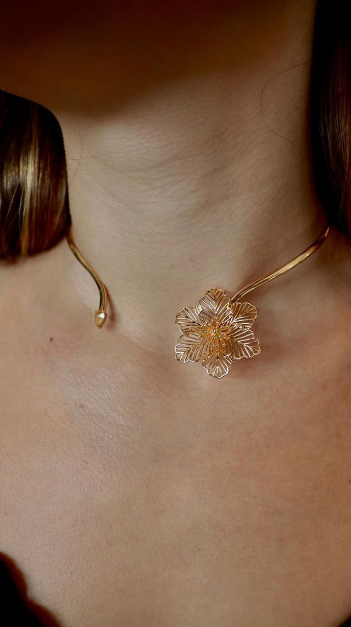 Colar dourado com pingente floral.